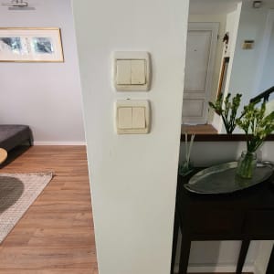 שני מתגים על קיר לבן בחדר עם רצפת עץ