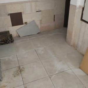 אריחים וכלי עבודה על רצפה, קיר עם חיפוי.