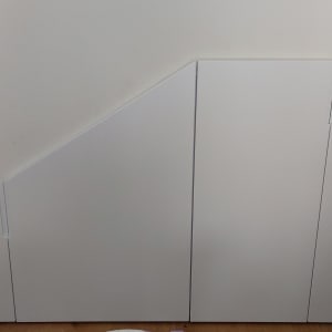 ארון לבן מתחת למדרגות עם דלתות משופעות