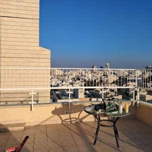 מעקה מתכת לבן על מרפסת עם שולחן עגול