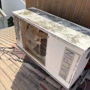 יחידת מיזוג אוויר על גג עם חוטים וקיר לבנים