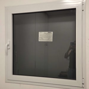 חלון אלומיניום עם ידית לבנה על קיר לבן