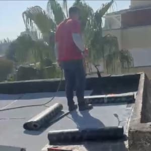 אדם עובד על איטום גג עם יריעות ביטומניות