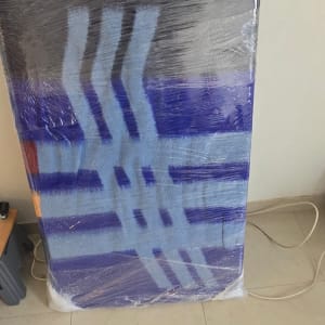 מזרן עטוף בשמיכת הובלה וסרט ניילון נצמד בדירה