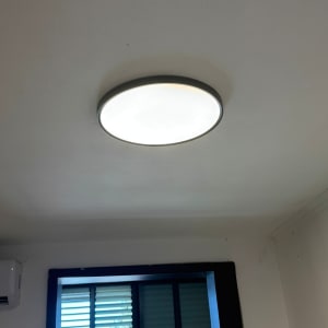 מנורה עגולה מותקנת על תקרה בחדר עם חלון