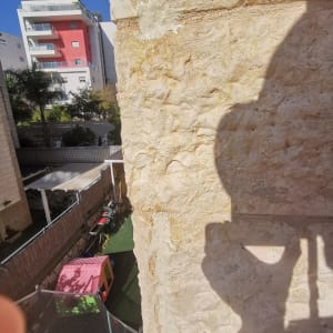 קיר אבן עם סימן פגיעה ושמש על הקיר