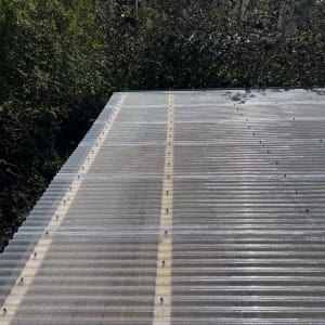 גג מתכת עם ברגים ועצים ברקע