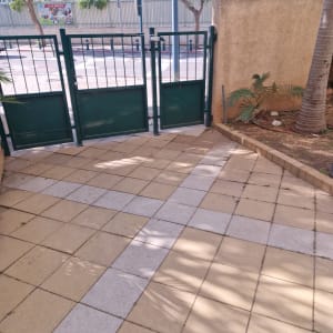 ריצוף חוץ עם צמחייה וגדר מתכת ירוקה