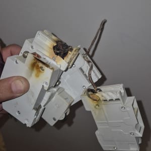 חוטים שרופים וממסר חשמלי פגום ביד חשמלאי