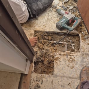 עובד חופר ברצפה עם מקדחה חשמלית