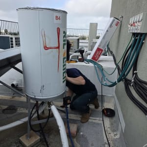 אדם עובד על דוד שמש על גג עם כלים וצינורות