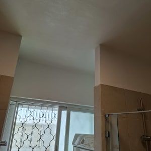 תקרה צבועה בחדר אמבטיה עם חלון ודלת זכוכית
