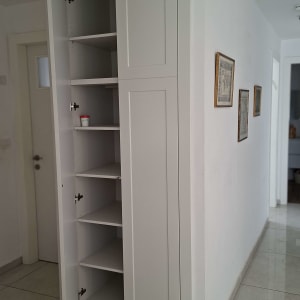 ארון כניסה לבן עם דלתות ציר ומדפים פנימיים במסדרון הבית