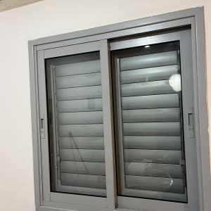 חלון עם תריסים אפורים על קיר לבן