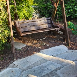 גג עשוי מקלות עץ מעל נדנדה בגינה