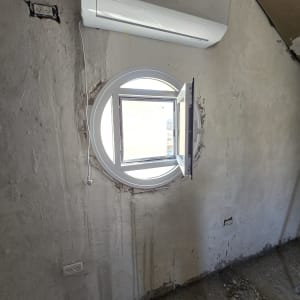 חלון עגול מאלומיניום בקיר בטון חשוף