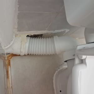 צינור שירותים מחובר לאסלה עם סימני נזילה