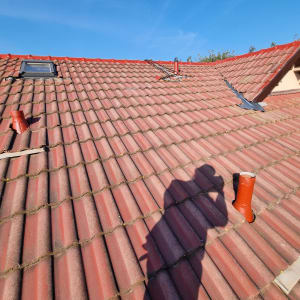 גג רעפים אדום עם חלון גג וצינורות אוורור