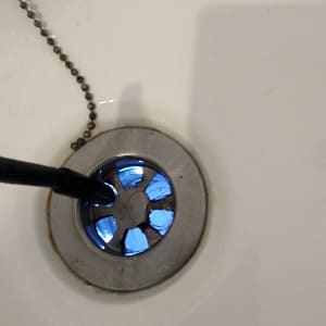 צינור שחור נכנס לניקוז כיור מתכת