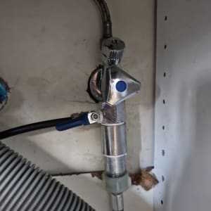 צינור מתכת עם ברז וכבל גמיש מתחת לכיור