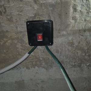 מתג חשמלי מותקן על קיר עם חוטים ירוקים