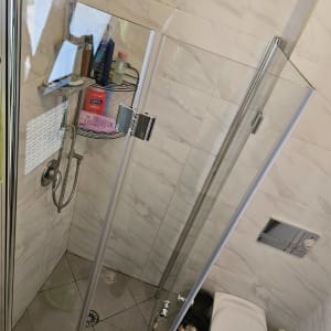 מקלחון זכוכית עם מוצרי טיפוח על מדף