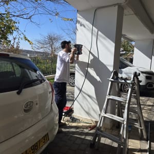 חשמלאי קודח בקיר עם מקדחה חשמלית