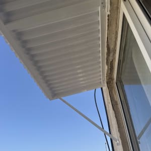 גגון אלומיניום לבן מותקן על קיר חיצוני מעל פתח בבית