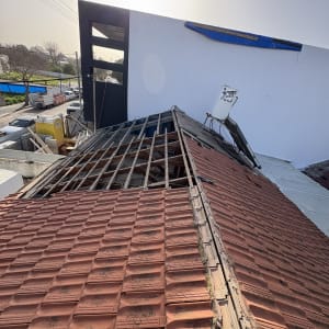 גג רעפים בתהליך תיקון עם שלט על הקיר