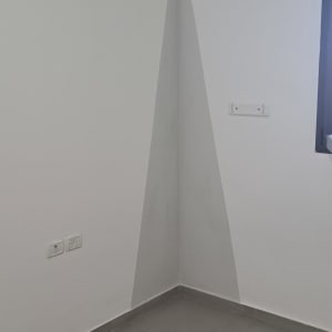 קיר צבוע בצבע אפור בהיר עם צורה גיאומטרית