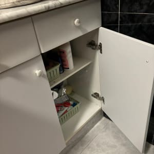 ארון מטבח פתוח עם מוצרי ניקוי וסלסלות אחסון