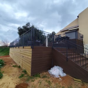 מעקה מתכת שחור על מדרגות עץ חום