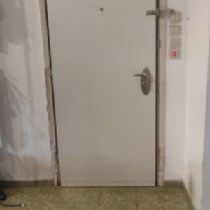 דלת עם ידית ומנעול, קיר לבן ורצפה מרוצפת