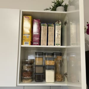 מיכלי אחסון שקופים עם דגנים וקטניות בארון מטבח