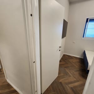 דלת לבנה פתוחה בחדר עם רצפת פרקט