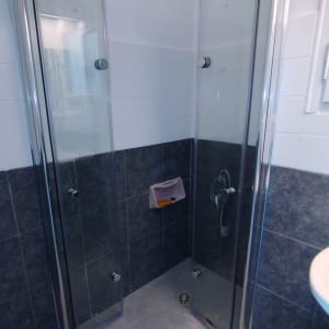 מקלחון זכוכית עם דלתות פתוחות ורצפת אריחים אפורה