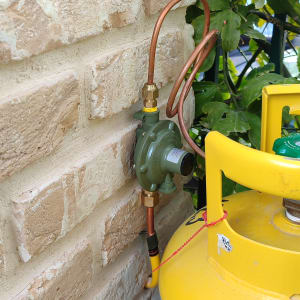 בלון גז עם צינור נחושת ליד קיר לבנים