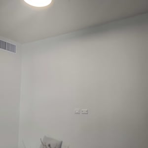 תאורה בתקרה עם קיר לבן ושולחן עם פרחים