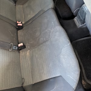 מושבי בד אחוריים של רכב המציגים לכלוך וכתמים לפני ניקוי ריפודים