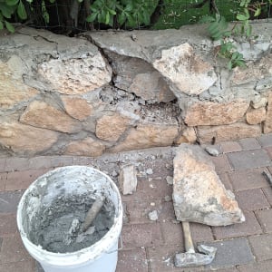 קיר אבן עם דלי מלט ופטיש לריצוף