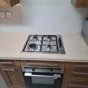 כיריים ותנור במטבח מודרני עם ארונות עץ.