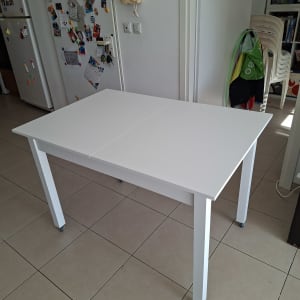 שולחן לבן על גלגלים במטבח עם מקרר וקישוטים