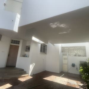 חצר עם קירות לבנים וצמחייה, צינור מים על הרצפה