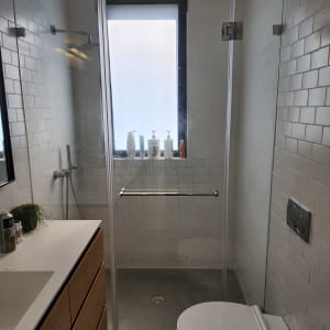 מקלחת עם ראש גשם ובקבוקי סבון על אדן החלון