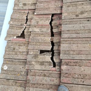 רעפים שבורים על גג עם רגל נראית בתמונה