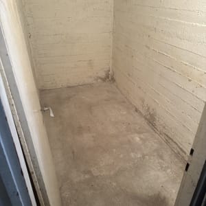 חדר ריק עם קירות בטון ודלת פתוחה