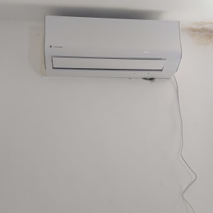 מזגן קיר לבן עם כבל חשמל תלוי