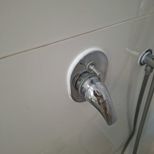 ברז מים מותקן על קיר אריחים בחדר אמבטיה
