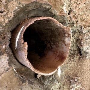 צינור חלוד שבור בקיר עם סימני רטיבות