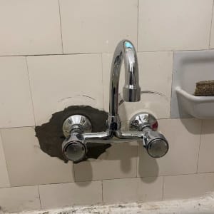 ברז מים מותקן על קיר עם תיקון טיח